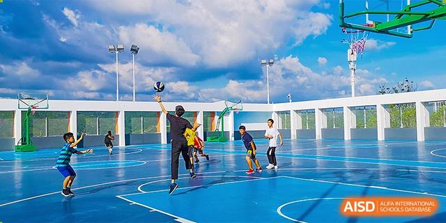 Students playing basketball on a blue outdoor court, with one student attempting a jump shot at BASIS International School Hangzhou (BIHZ).