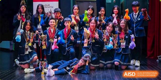 A large group of excited students holding up awards and medals while posing for a picture on a stage after an event at BASIS International School Hangzhou (BIHZ).