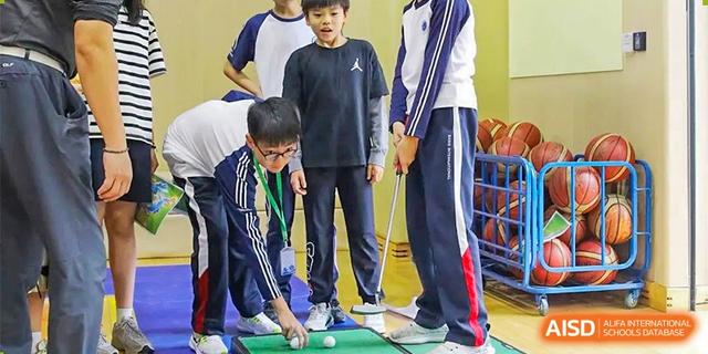 Two male students playing a game of indoor mini-golf or billiards at a school event at BASIS International School Hangzhou (BIHZ).