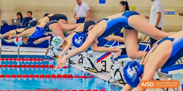 A close-up of a swimmer on a starting block about to dive into the pool during a race at BASIS International School Hangzhou (BIHZ).