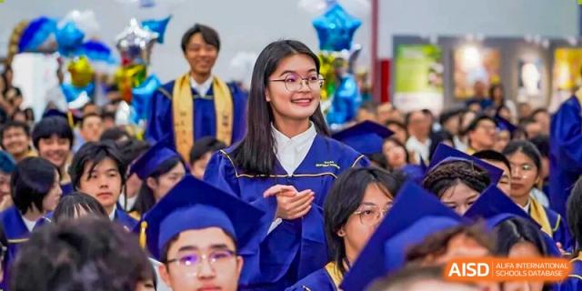A smiling female graduating student from World Leading Schools Association wearing a blue cap and gown.