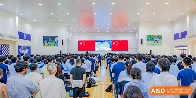 Students from World Leading Schools Association attending a formal event or assembly in a large hall with the Chinese flag displayed.