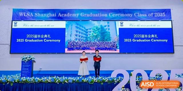 Two speakers addressing the audience from a stage during the World Leading Schools Association "Academy Graduation Ceremony."