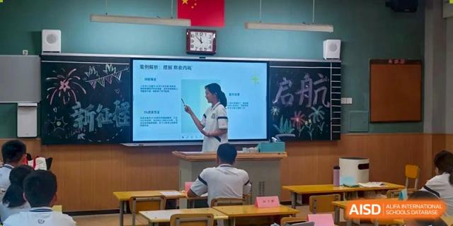 A Zhengzhou No.9 High School International Department student giving a presentation in front of the class using a large digital screen.