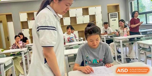 A Zhengzhou No.9 High School International Department teacher assisting a female student individually with her work at a desk.