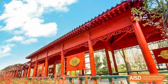 A close-up view of a traditional red building structure, possibly a gate or pavilion, on the campus of Zhengzhou No.9 High School International Department.