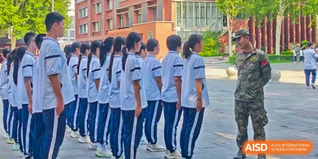A line of Zhengzhou No.9 High School International Department students in school uniforms standing side-by-side outdoors.