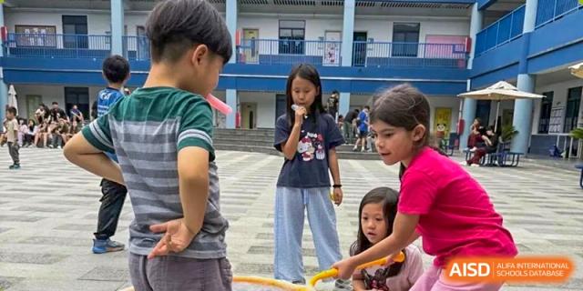 Students participating in a school fair or outdoor activity on the steps and paved area of the campus at QSI International School of Dongguan.