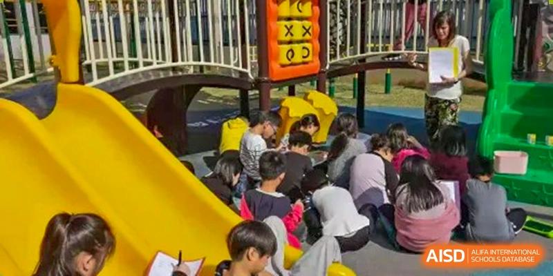 Children playing near a yellow slide on the playground during an outdoor recess or event at QSI International School of Dongguan.
