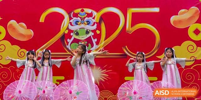 A young female student performing a song in a traditional-style dress in front of a colorful backdrop at QSI International School of Dongguan.
