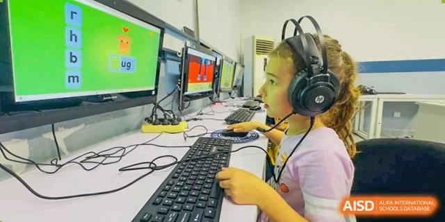 A student wearing headphones working on a computer with a large keyboard in a lab or classroom at QSI International School of Dongguan.
