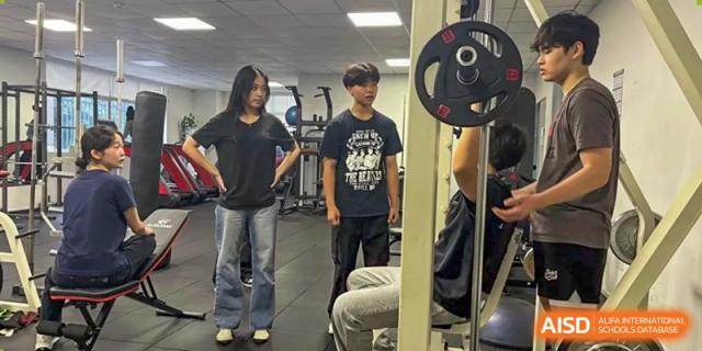 A group of students exercising or socializing in the school's fitness or weight room at QSI International School of Dongguan.