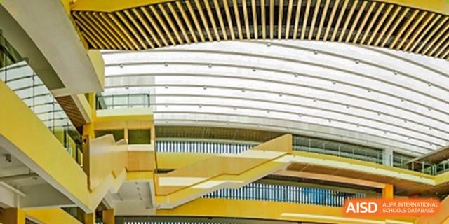 A close-up of the modern architectural design of a building at Guangzhou Huamei International School, showing curved white railings and yellow stairways.