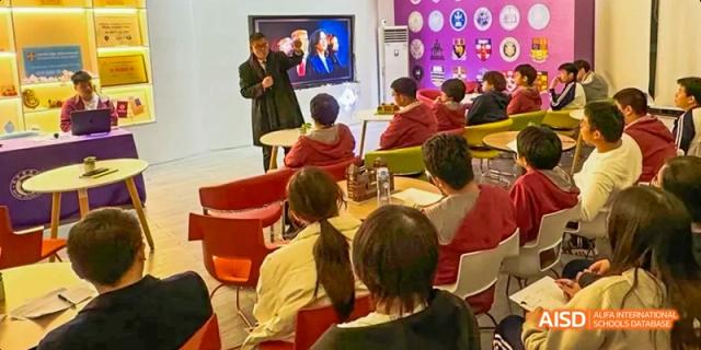 A teacher instructing students while standing near a large digital screen displaying content. Beijing No.4 High School International Courses Jialian Campus.
