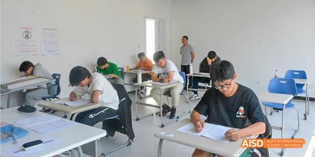 Students sitting at desks in a bright, modern classroom, focused on writing or studying. Beijing No.4 High School International Courses Jialian Campus.