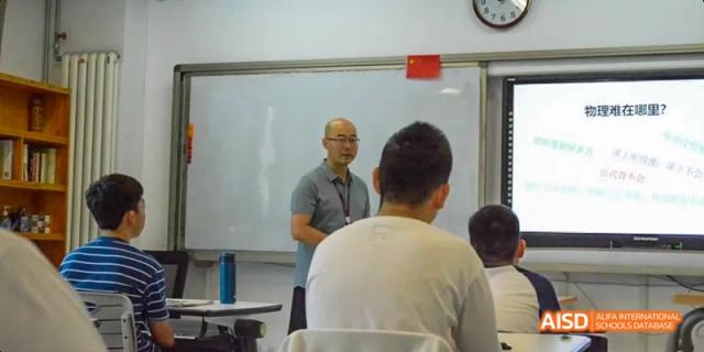 A male teacher in a gray shirt addressing students who are sitting in class. Beijing No.4 High School International Courses Jialian Campus.