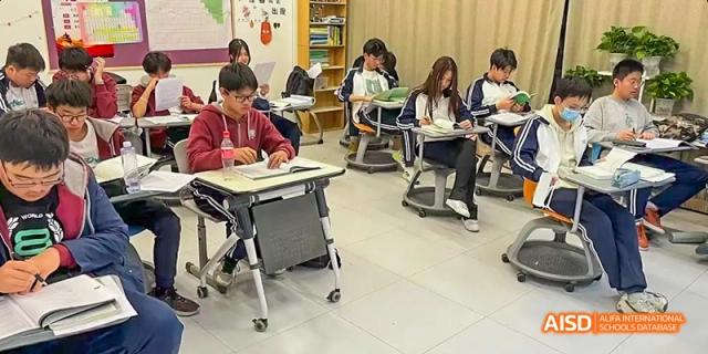 Students seated at individual desks in a classroom, engaged in study during a small group session. Beijing No.4 High School International Courses Jialian Campus.