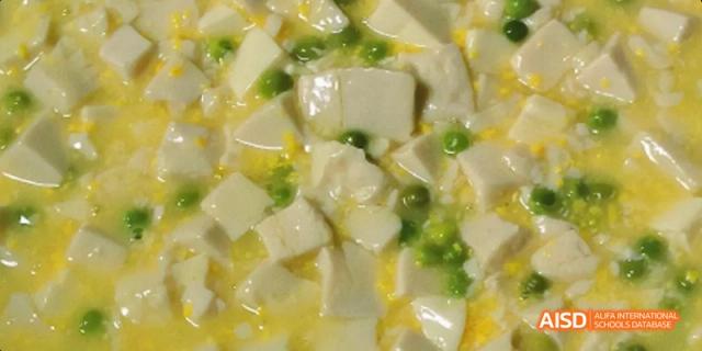 A light-colored dish of silken tofu cubes in a mild sauce, garnished with green onions. Beijing No.4 High School International Courses Jialian Campus.