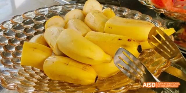 A bowl of peeled, whole, yellow food items that appear to be steamed bananas or potatoes. Beijing No.4 High School International Courses Jialian Campus.