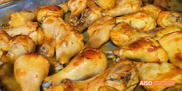 A close-up view of roasted chicken legs and thighs with glossy, browned skin. Beijing No.4 High School International Courses Jialian Campus.