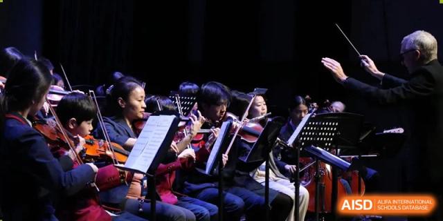 Students playing string and wind instruments as part of a school orchestra during a performance at Yew Chung International School of Beijing.