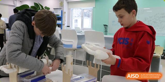 A student working on a white model or structure with a teacher in a bright classroom at Yew Chung International School of Beijing.