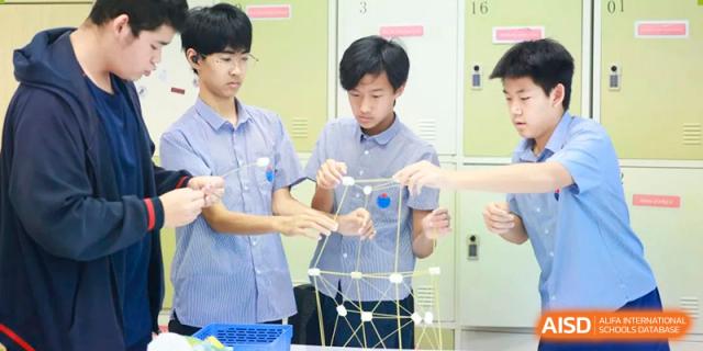 Students working together to build a geometric structure using sticks and connectors in a science or design class at Yew Chung International School of Beijing.