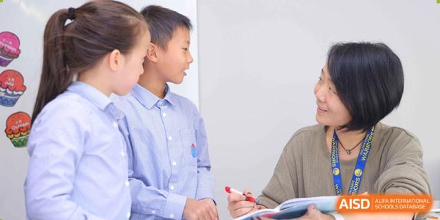 Two students collaborating on a task or project, writing on a whiteboard or paper at Yew Chung International School of Beijing.