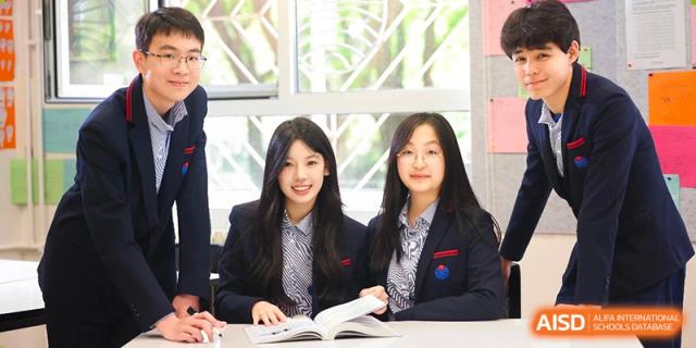 Two female students in school blazers smiling while reading books at Yew Chung International School of Beijing.