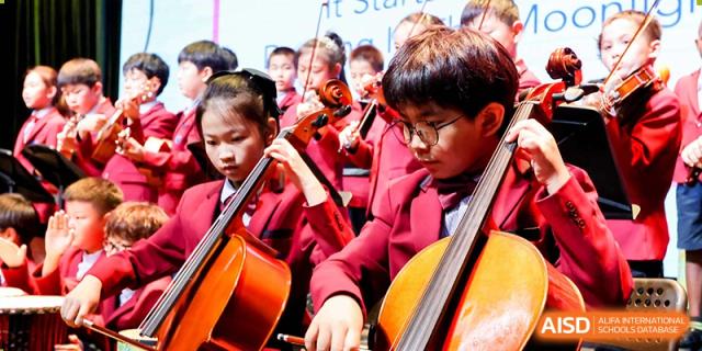 Close-up of students in school uniform playing the cello and violin in a school ensemble at Yew Chung International School of Beijing.