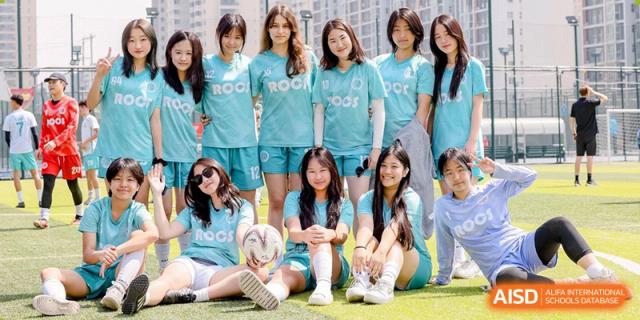A group of female students in light blue sports uniforms posing outdoors on the field at Yew Chung International School of Beijing.
