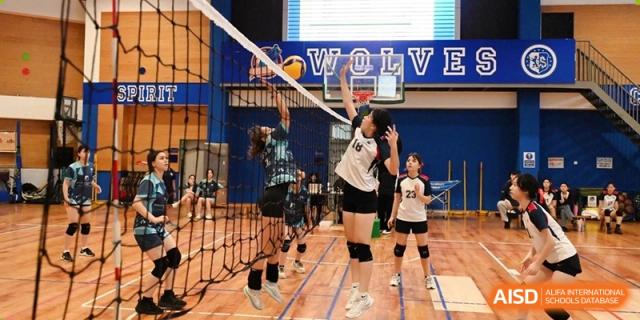 Female students jumping at the net during a volleyball game at Yew Chung International School of Beijing.