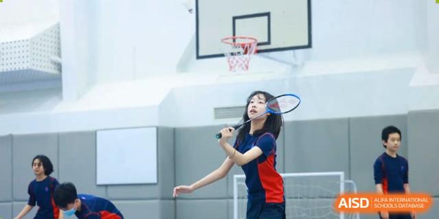 A female student playing badminton or tennis on an outdoor court at Yew Chung International School of Beijing.