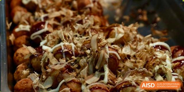 Close-up of a serving of Takoyaki (Japanese octopus balls) topped with sauce and bonito flakes, served at Yew Chung International School of Beijing.