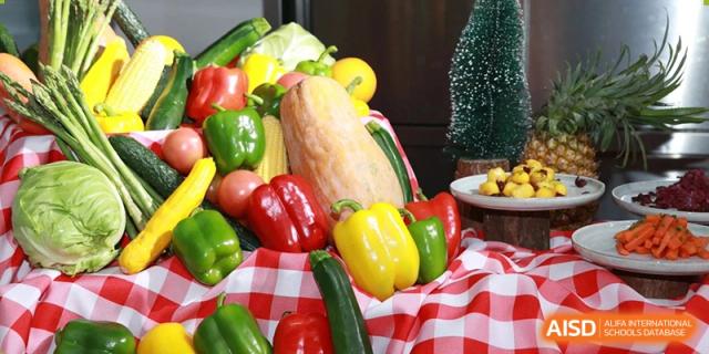 An arrangement of colorful fresh produce, including corn, squash, and red and yellow bell peppers, displayed at Yew Chung International School of Beijing.