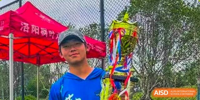 A smiling student holding a trophy decorated with ribbons after a competition or event at Maple Leaf International School Chongqing.