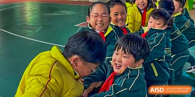 A close-up of several elementary school-age children in school uniforms laughing and smiling happily at Maple Leaf International School Chongqing.