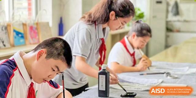 A female student being guided by a peer or a teacher while working on a project or experiment in a classroom at Wuxi Big Bridge Academy.