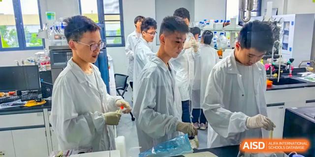 A group of male students in white lab coats working together on an experiment in a science lab at Wuxi Big Bridge Academy.
