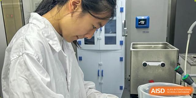 A student in a lab coat working with scientific equipment in a clean, modern lab at Wuxi Big Bridge Academy.