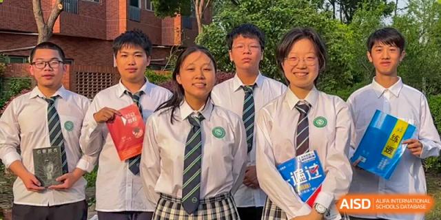 A group of smiling students in school uniforms posing for a picture outdoors at Wuxi Big Bridge Academy.