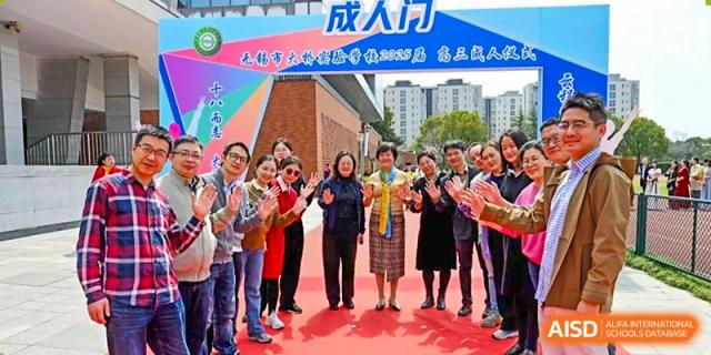 A group of teachers or staff posing for a photo under an archway at an event held at Wuxi Big Bridge Academy.