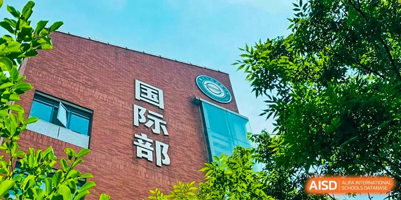 Exterior view of a building at Wuxi Big Bridge Academy featuring the bold characters for "International Division" (国际部) on the brick wall.