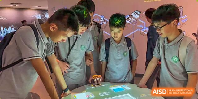 A group of students engaging with an interactive digital table or project in a classroom at Wuxi Big Bridge Academy.