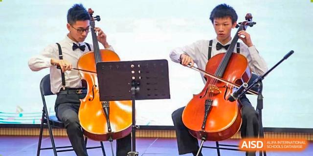 A close-up of a student playing the cello or another string instrument during an orchestra or music performance at Wuxi Big Bridge Academy.