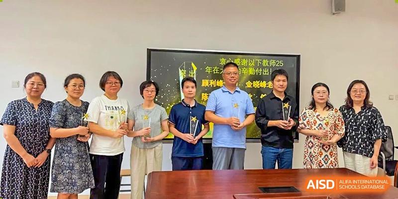 Teachers and school administrators posing with a presentation plaque or award at Wuxi Big Bridge Academy.