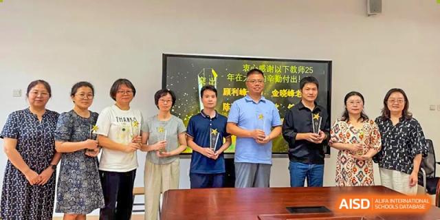 Teachers and school administrators posing with a presentation plaque or award at Wuxi Big Bridge Academy.