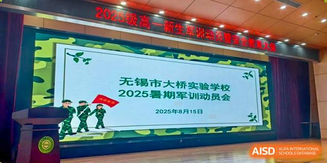 A large screen displaying a welcome message for the 2025 summer military training and orientation at Wuxi Big Bridge Academy.