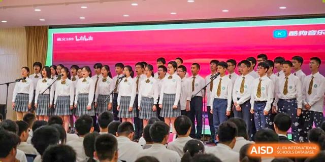 A choir or group of female students singing on stage in their school uniforms at Wuxi Big Bridge Academy.