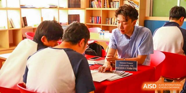 A student from Zhuhai Oriental Yinghua International Academy signing a form or registering at an event table.